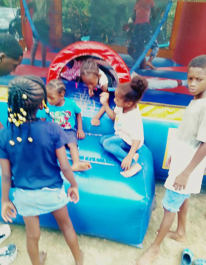 Children wait their turn to play inside the bouncy castle at a back-to-school treat in Clark’s Town, Clarendon.