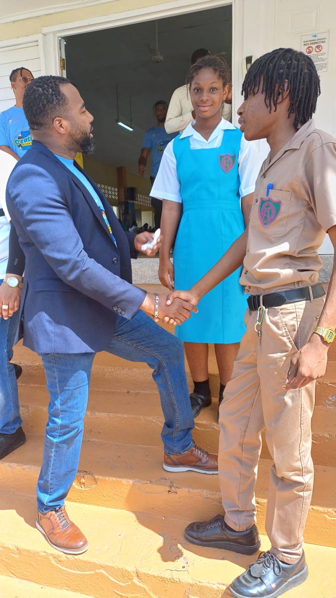 Chief Executive Officer of the Universal Service Fund (USF), Charlton McFarlane (left), greets grade 11 student at William Knibb Memorial High School in Trelawny, Amere Pugh (right), at the USF Influencer Creative Workshop held at the St Hilda’s High Sch