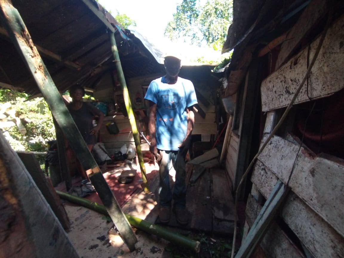 Rudy Campbell walks through a section of the damaged wooden house as his common-law wife Delmina Pusey looks on.