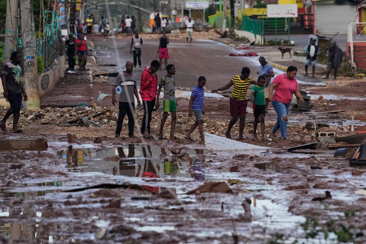 People walk through Santa Cruz, Jamaica, after Hurricane Melissa passed.