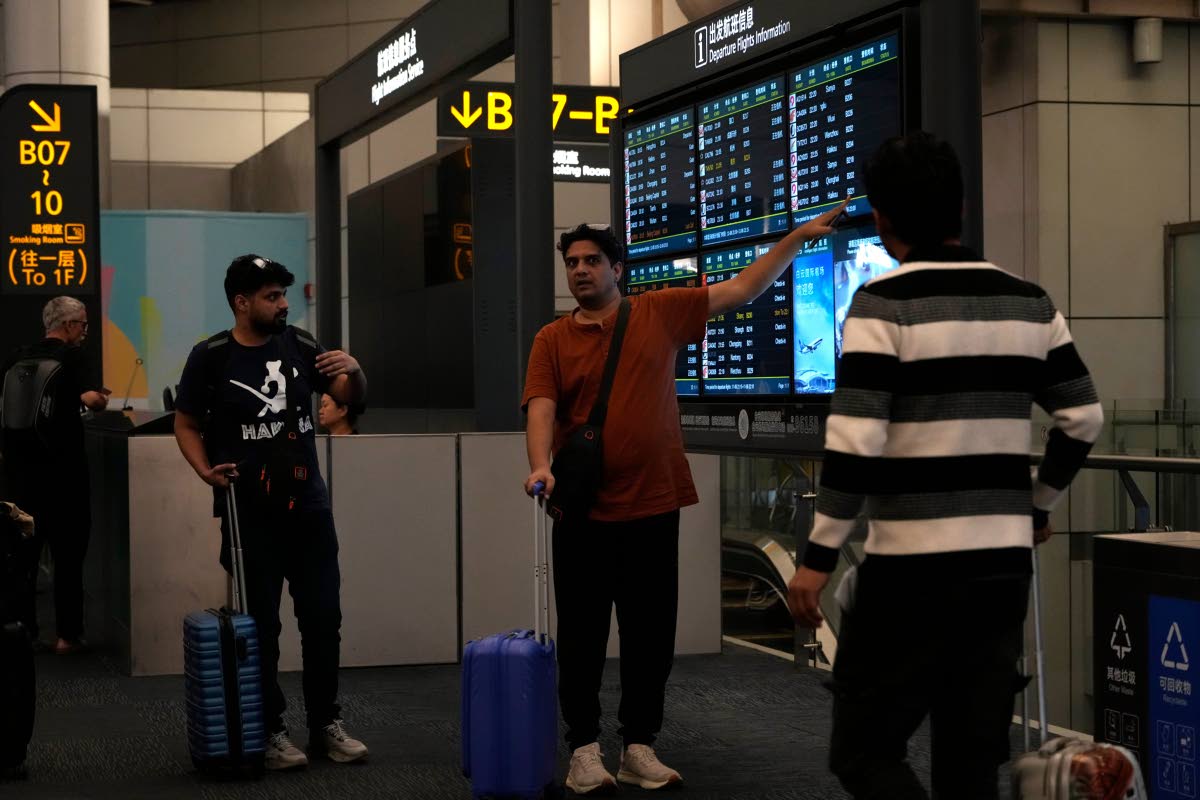 Foreigners look at a display board for flights at Baiyun airport in Guangzhou, southern China’s Guangdong province, on November 6, 2025.