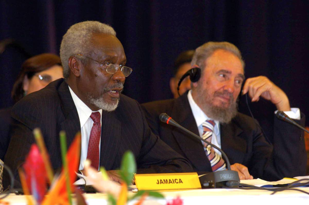 Prime Minister P.J. Patterson (left) addresses a press conference following the 2nd CARICOM/Cuba Summit in Barbados on December 8, 2005.  Listening at right is Cuban President Fidel Castro.