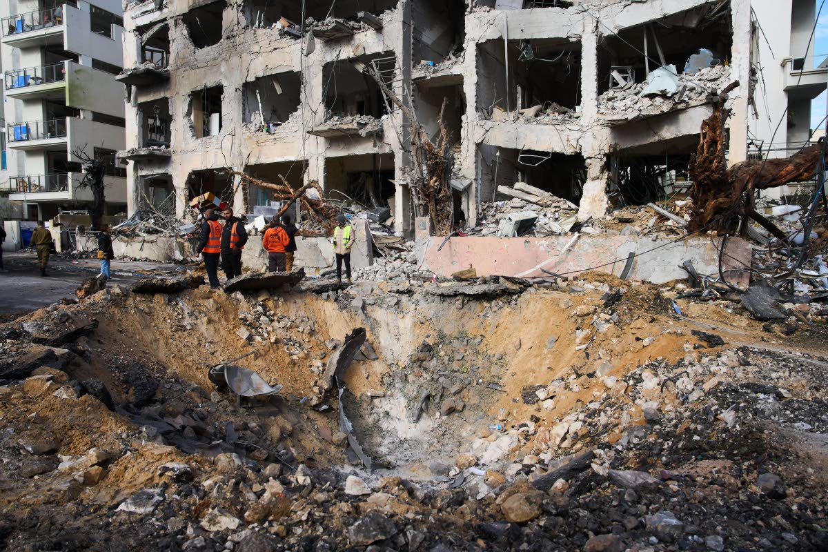 Rescue workers and military personnel survey the scene of a direct hit a day after an Iranian missile struck in Tel Aviv, Israel, Sunday.