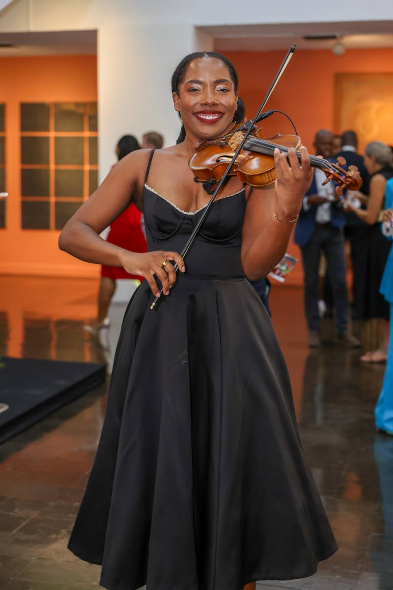 Adding a melodic touch to the evening’s art experience, Dayna Palmer takes a moment from her performance to pose for a photo.