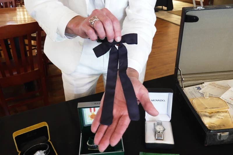 Auctioneer Jonathan Klunk shows a black bow tie worn by KFC founder Harland Sanders, Wednesday, July 22, 2026, in Shelbyville, Ky. (AP Photo/Dylan Lovan)
