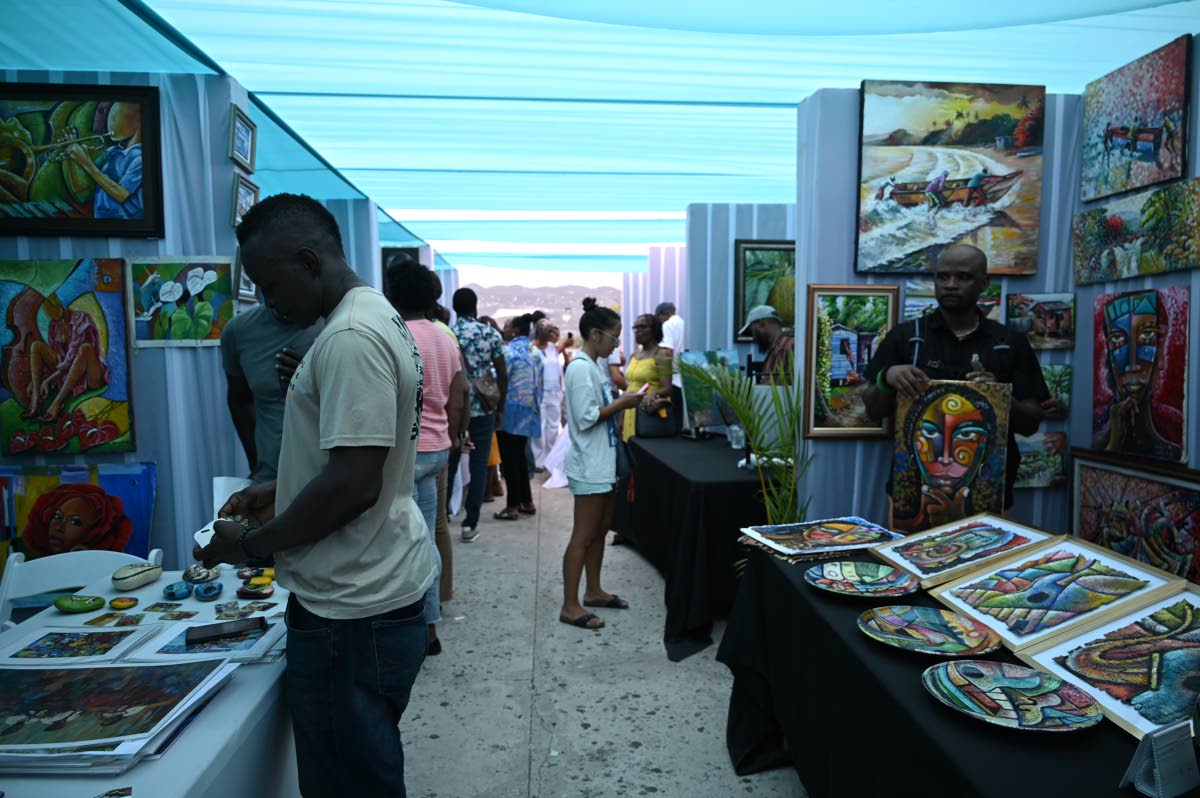 Visitors browse artworks on display during the inaugural Art on the Bay exhibition at Pier 1 in Montego Bay.
