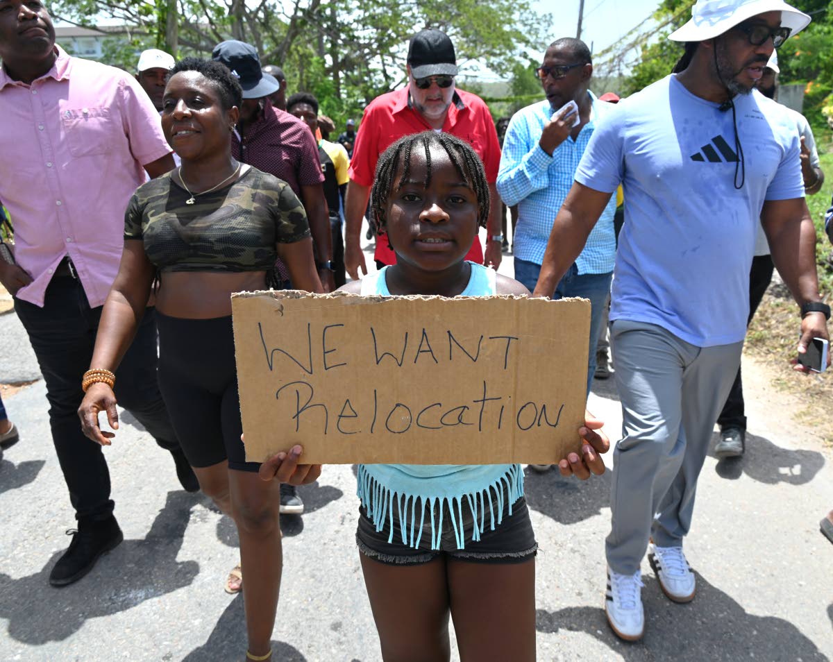 A young resident of Cooper’s Pen holds a placard during a visit to the area by Opposition Leader Mark Golding and other officials on Thursday.