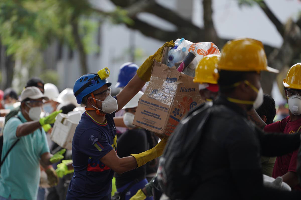 Rescuers pass food packages for rescue teams and volunteers searching through the rubble four days after an earthquake hit Cali, Colombia, last Friday.