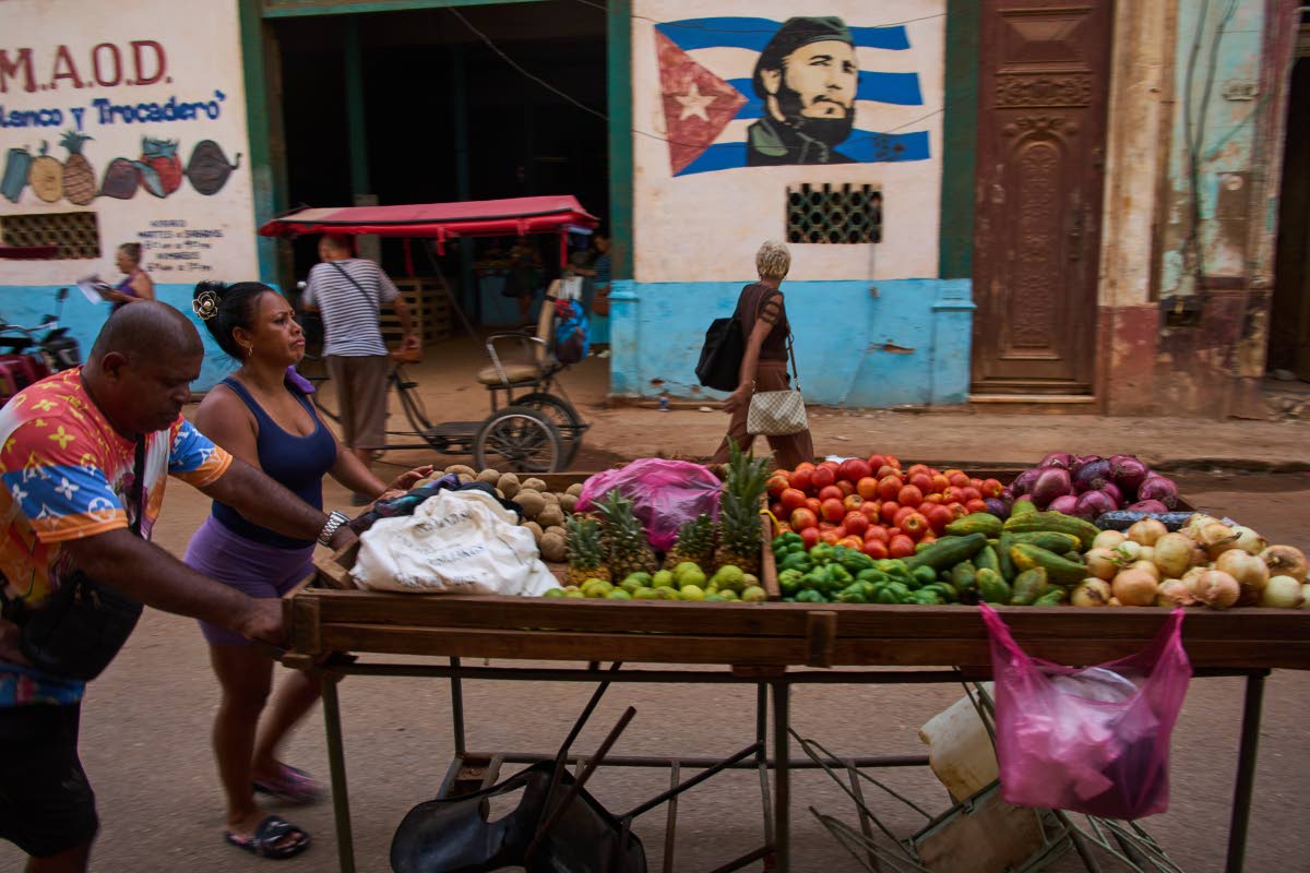 Street vendors push their cart of vegetables past a mural of Fidel Castro in Havana, Cuba.
