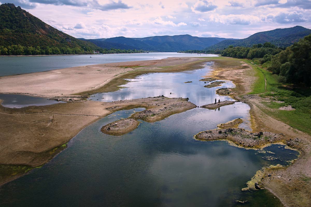People walk on sandbanks exposed by record-low water levels in the Danube River after drought and extreme heat near Nagymaros in Hungary, on August 18, 2026.