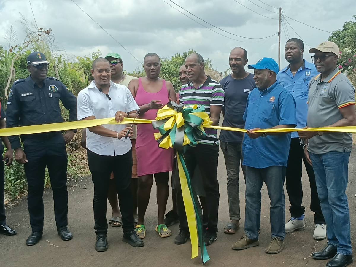 Floyd Green (centre), minister of agriculture, fisheries and mining, and community farmer Aslyn Parchment cut the ribbon to officially open and hand over the 550-metre Newcombe Valley-to-Amos Lane Farm Road in Pedro Plains, St Elizabeth. Sharing in the occ