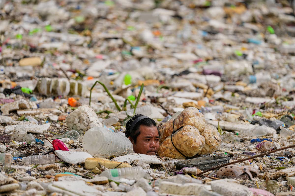 A worker uses improvised floats while trying to clear a sea of garbage and debris brought by intense monsoon rains at the Redemptorist Water Channel in Paranaque city, Metro Manila, Philippines, on August 11.