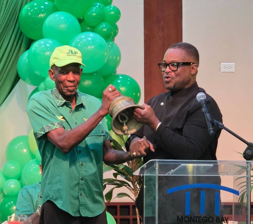 Heroy Clarke (right), the sole nominee for the Jamaica Labour Party’s deputy leadership of Area Council Four, receives the party’s symbolic bell from outgoing deputy leader J.C. Hutchinson after his nomination at Sunday’s Area Council Four meeting at