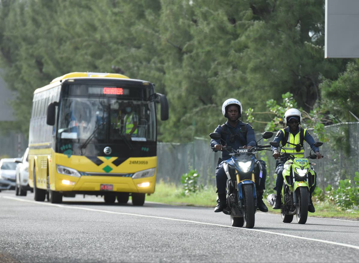 A Jamaica Urban Transit Company bus carrying third country nationals who arrived in the island on Tuesday departs from the Norman Manley International Airport in Kingston under police escort.