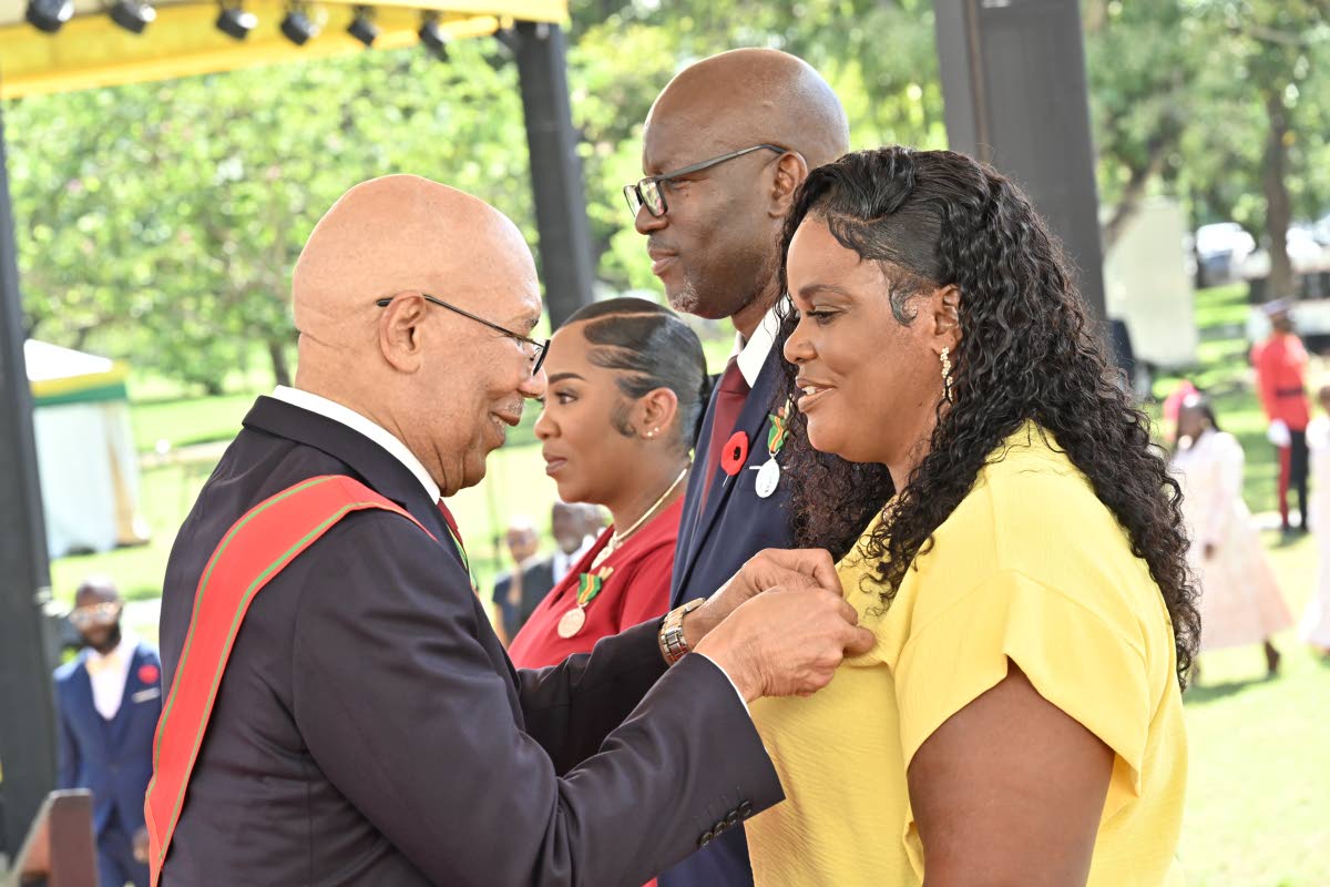 Governor-General Sir Patrick Allen pins the Badge of Honour for Gallantry on Susan Higgins as fellow recipients Councillor Scean Barnswell (centre) and Danielle Ann-Marie Barnswell look on during the National Honours and Awards Ceremony.
