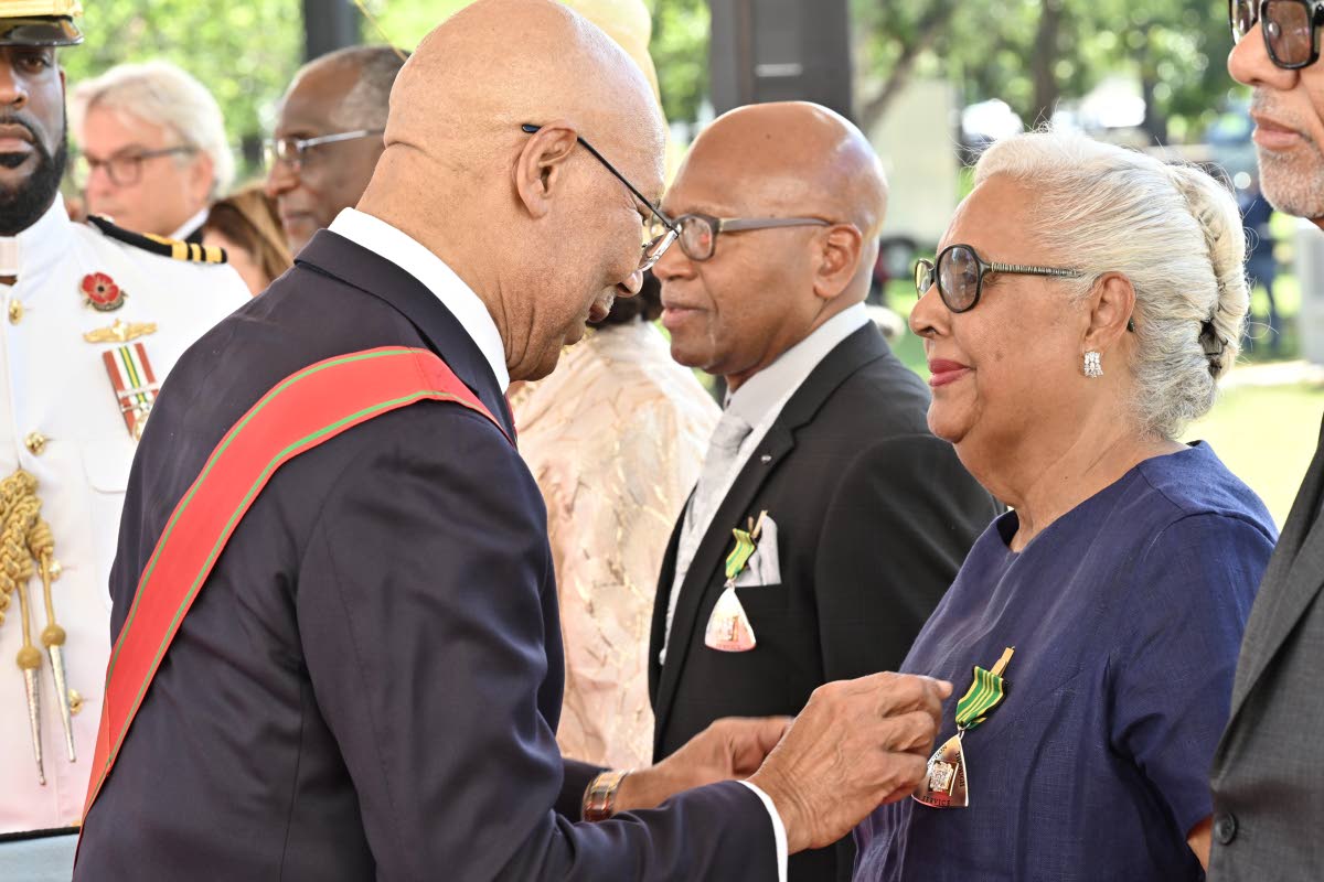 Governor-General Sir Patrick Allen pins the Order of Distinction in the Rank of Officer on Marjorie Kennedy during the National Honours and Awards Ceremony 2026 at King’s House on Monday. Also pictured is fellow recipient Michael Jones (second right), wh