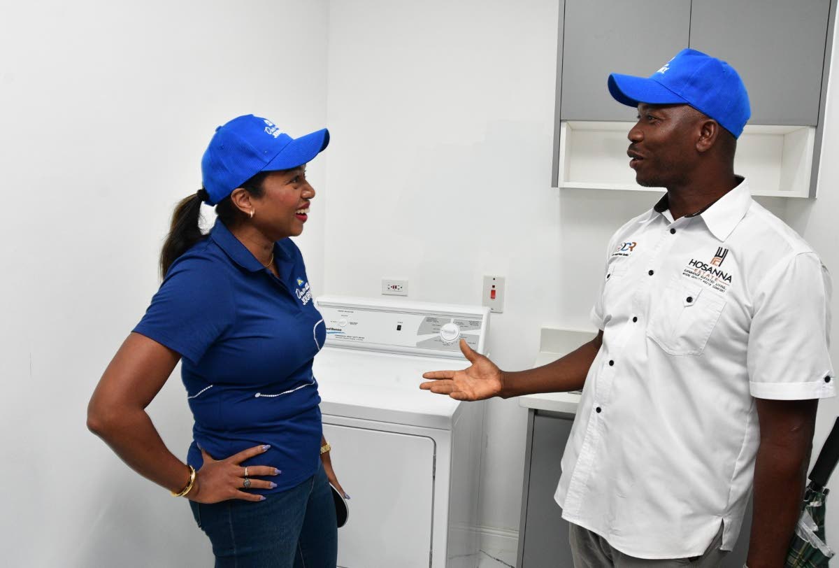  Luwanna Williams, managing director of JN Bank, listens as Delroy Reid, founder and director of DCR Construction and Development Limited, explains the features of a model unit at Hosanna Estate.