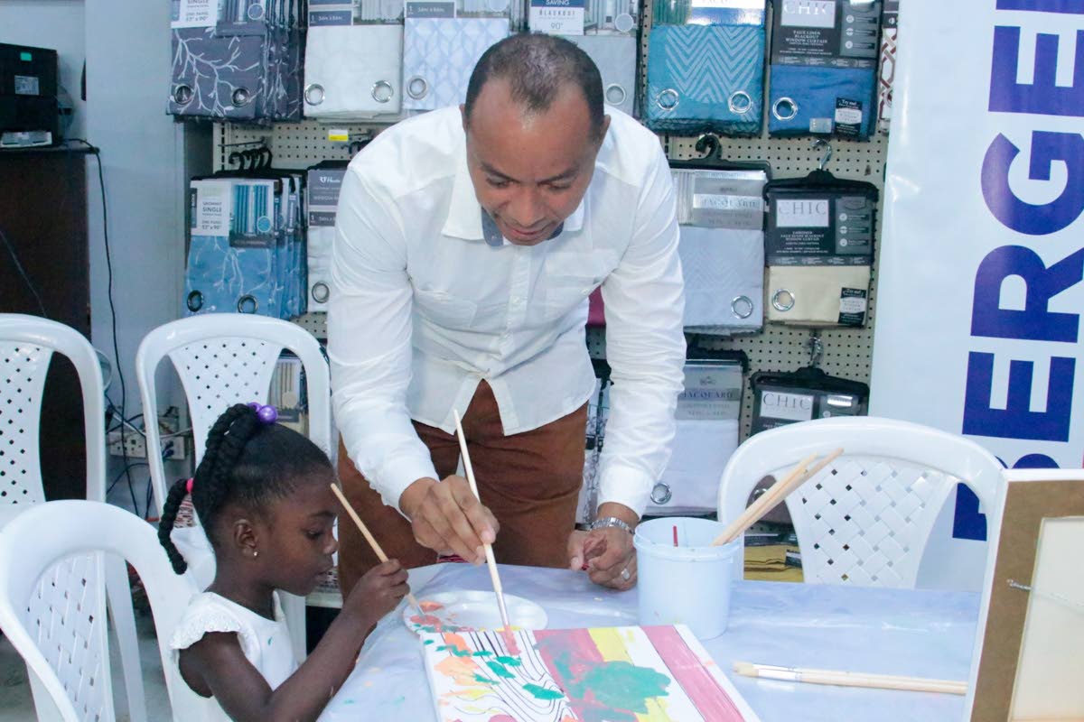 Contributed  Photos
Zhuri-Joy Crawford shows off her painting skills to the Linton Johnson, general manager of Berger Paints Jamaica Ltd, at H&L Rapid True Value on Constant Spring Road recently.