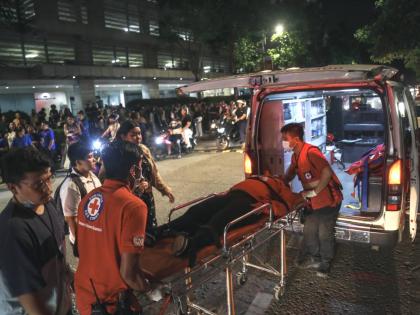 Medical workers load a resident into an ambulance as others stay outside buildings after a strong earthquake struck Cebu city, central Philippines, on Tuesday, September 30, 2025. (AP Photo/Jacqueline Hernandez)