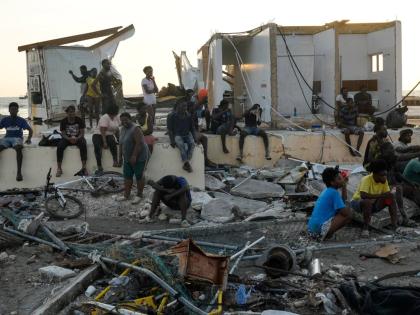 People gather among debris near a bridge in Black River, St Elizabeth, Jamaica, in the aftermath of Hurricane Melissa.