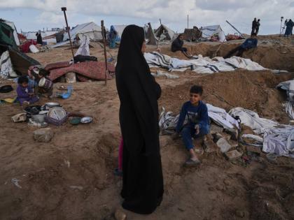 Palestinians inspect the damage at a displacement camp following an Israeli strike in Gaza City.