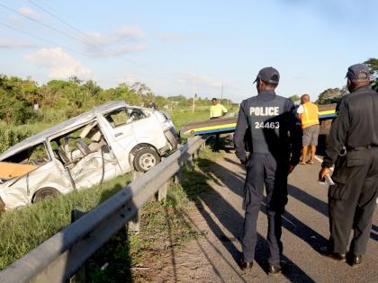 
In this October 2025 photo police officers are seen at a scene of an accident, as a wrecker removes the Toyota Hiace minibus that crashed along West-East leg of Highway 2000, close to the Vineyard Toll Plaza. 