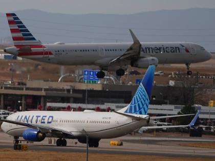 An American Airlines jetliner lands on a runway as a United Airlines plane waits for clearance to take off as high winds strafe Denver International Airport Thursday, March 12, 2026, in Denver. (AP Photo/David Zalubowski)