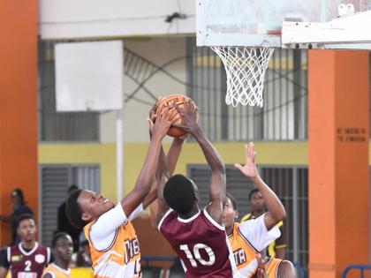Andra Morgan (left) of Manchester High School  moves to block a shot by Antonio Kerr of Herbert Morrison during their ISSA Rural basketball Under-16 finals at GC Foster College yesterday.