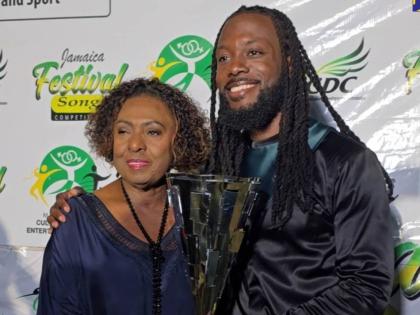 Minister of Culture, Gender, Entertainment and Sport, Olivia Grange (left), presents 2026 Jamaica Festival Song Competition winner dBurnz with his trophy, at the grand finale of the competition held at the Ranny Williams Entertainment Centre in St Andrew o