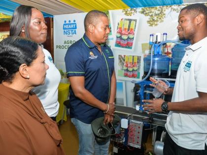 Instructor of Mechatronics and Mobile Robotics at HEART/NSTA Trust, Derrick Rochester Campus, Dihanroy Mitchell (right), explains the use of Mechatronics in Agro-Food and Beverage Processing to Minister of Agriculture, Fisheries and Mining, Floyd Green (th