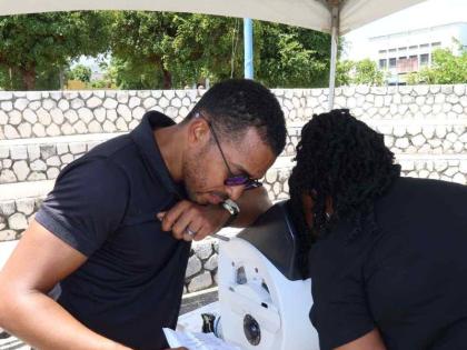 Carlington Willis, general manager of Eye Q Optical, provides a free eye examination as part of the vision screening services offered at the Kingston Public Hospital 250th Anniversary Health and Wellness Fair. 