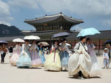 Visitors holding umbrellas to avoid sunshine leave the Gyeongbok Palace in Seoul, South Korea, Wednesday.