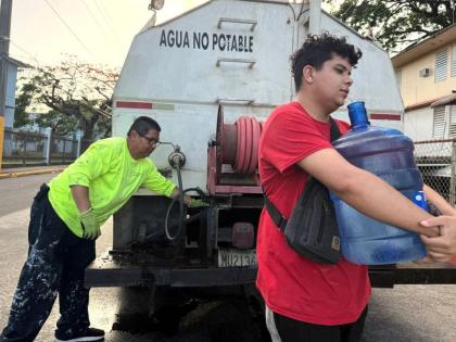 Bryan Pérez hauls a five-gallon water jug to his apartment in the Villa Kennedy public housing complex in San Juan, Puerto Rico, June 10, 2026.