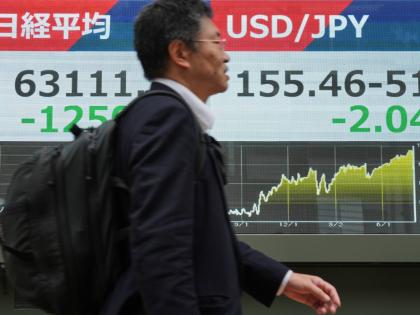 A person walks past an electronic board showing Japan’s Nikkei index and U.S. dollar and Japanese yen exchange rate at a securities firm in Tokyo Monday, Aug. 3, 2026. (AP Photo/Eugene Hoshiko)