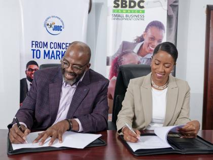 Harold Davis (left), Jamaica Business Development Corporation Acting CEO, Andrea Dempster-Chung, Kingston Creative co-founder and executive director, all smiles while signing a non-binding agreement in July. It will formally joining Jamaica’s national Sm