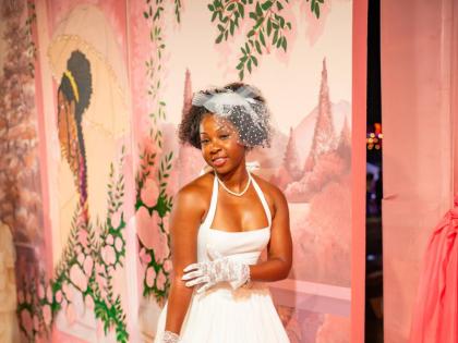 New York-based correctional officer Shanell Maitland brings vintage glamour to Milk & Honey in a white BABYBOO halter midi dress, styled with a birdcage veil fascinator for a timeless finish.