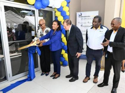 Minister of Finance and the Public Service, Fayval Williams (fifth right), and Minister without Portfolio in the Office of the Prime Minister with responsibility for Efficiency, Innovation and Digital Transformation, Audrey Marks (fourth right) cut the rib