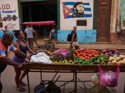 Street vendors push their cart of vegetables past a mural of Fidel Castro in Havana, Cuba.