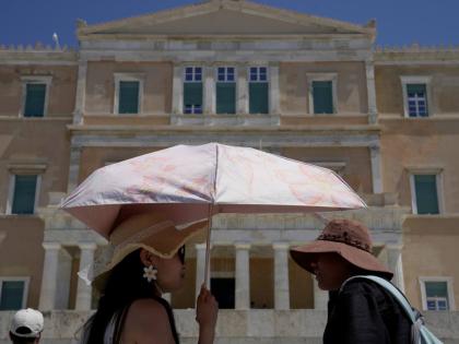 Tourists wearing hats visit the Tomb of the Unknown Soldier outside the Greek Parliament in Athens, Greece.