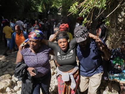 People watch as the bodies of their relatives who were killed in a gang attack are carried away by morgue workers in the Kenscoff neighborhood of Port-au-Prince, Haiti, Monday, Aug. 24, 2026. (AP Photo/Odelyn Joseph)