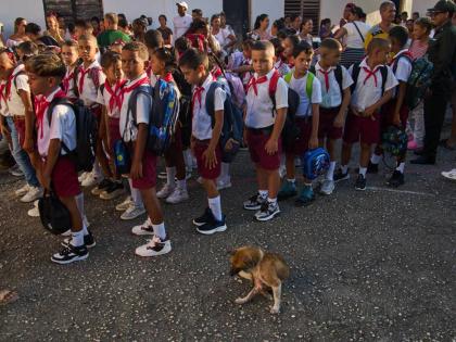 Children line up for their national anthem in the school courtyard where a stray dog sits by on the first day back to school in Minas, Cuba's Havana province, Tuesday, Sept. 1, 2026. (AP Photo/Ramon Espinosa)