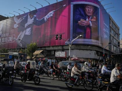 Motorcyclists ride past a billboard depicting U.S. President Donald Trump inside a catering container in downtown Tehran, Iran, Saturday, Aug. 29, 2026. 