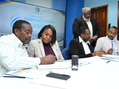 Minister with Responsibility for Land Titling and Settlements in the Ministry of Economic Growth and Infrastructure Development, Robert Montague (left), signs contracts for the construction of semi-permanent housing solutions for Hurricane Melissa-affected