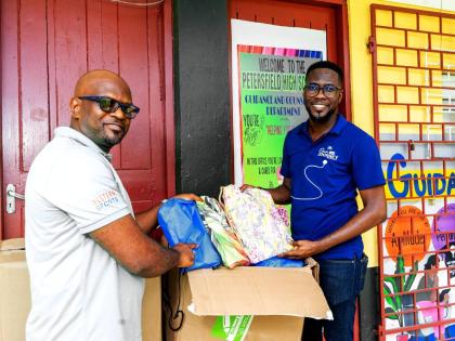 Omar Wright (right), lead, Environment and Community Development at the JN Foundation, hands over back-to-school-supplies to Roan Green, principal of Petersfield High School in Westmoreland. JN Foundation made the donation to the institution during a visit