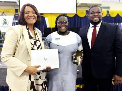 Anastacia Williams (centre) shows the mobile phone she relied on for university coursework alongside the laptop she received through a partnership involving AdventHealth and Andrews Memorial Hospital. Sharing in the moment are Dr Audrey Gregory (left), sen