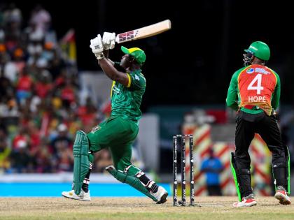 Jamaica Kingsmen captain, Rovman Powell (left), swings for the fences during a Republic Bank Caribbean Premier League Qualifier against the Guyana Amazon Warriors on Friday night. Amazon Warriors wickeetkeepeer Shai Hope looks on.