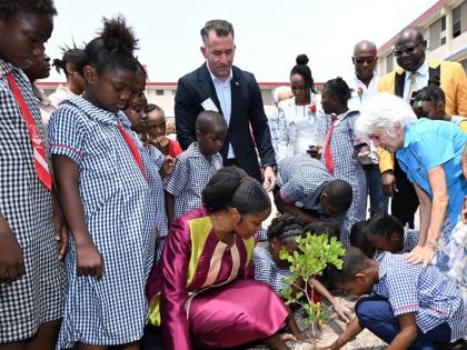 Principal of Tavares Gardens Primary School, Terriann Nisbeth (bending, front row), is joined by her students as they plant a tree during the official launch of the 2026-2027 Trees for Peace Competition on Monday at Tavares Gardens Primary School in Kingst