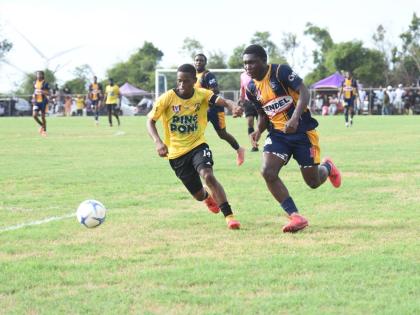 Munro College’s Izion Fraser (right) tries to outpace Black River High’s De Shawn Smith during their ISSA daCosta Cup Zone D preliminary round match at Munro playfield yesterday.