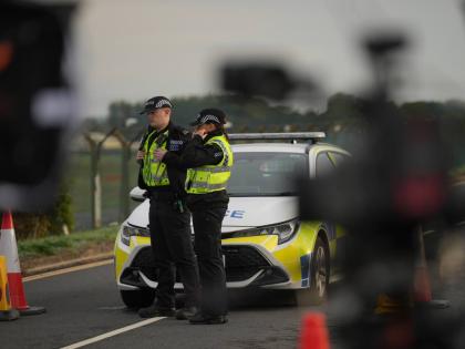 Police officers guard a road leading to RAF Fairford, after an incident in Fairford, England, Monday.