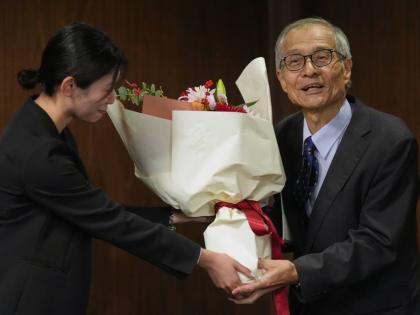 Japanese chemist Kenso Soai receives a bouquet of flowers from a university staff member before the press conference at Tokyo University of Science in Tokyo, Wednesday, after winning the Nobel Prize in chemistry. 